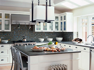 bright, functional kitchen space features a gorgeous backsplash with natural stone tiles