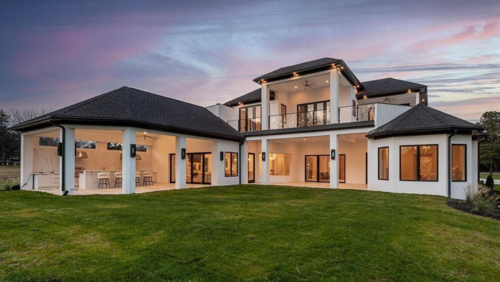 the rear of a luxe Mediterranean home with covered lanai space with an outdoor kitchen