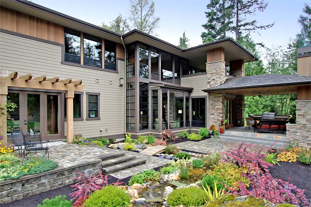 rear view of a luxury home with outdoor living spaces off the guest suite, dining nook, and upstairs primary suite