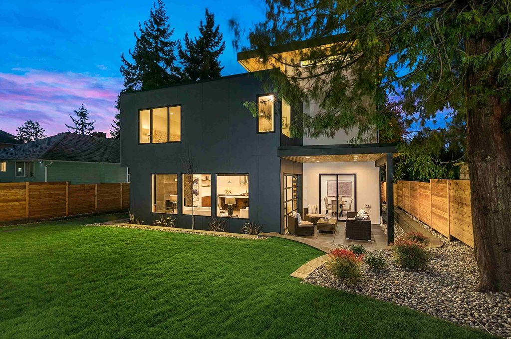 the rear view of a three-level modern house with a rooftop deck beside the third level rec room