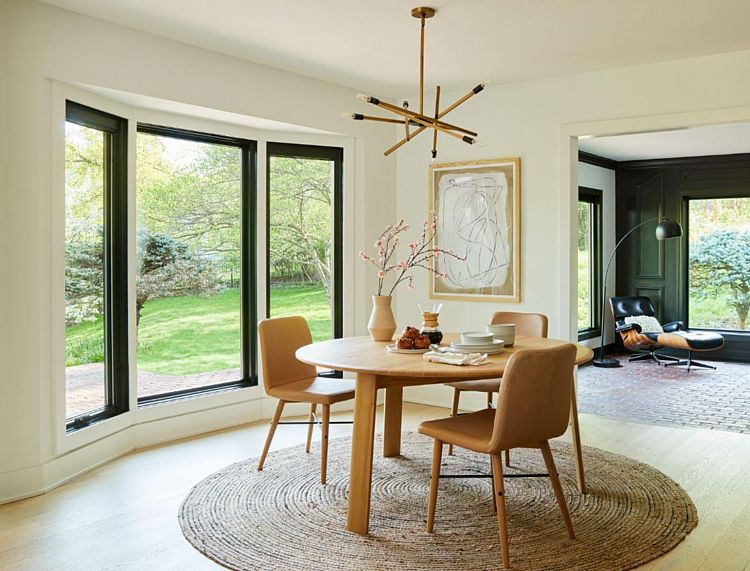A Dining Area with a Bowed Wall of Wood Picture and Casement Windows