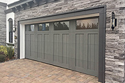 A Sleek Gray Garage Door on a Transitional Home with Dark Trim and Grayscale Stone